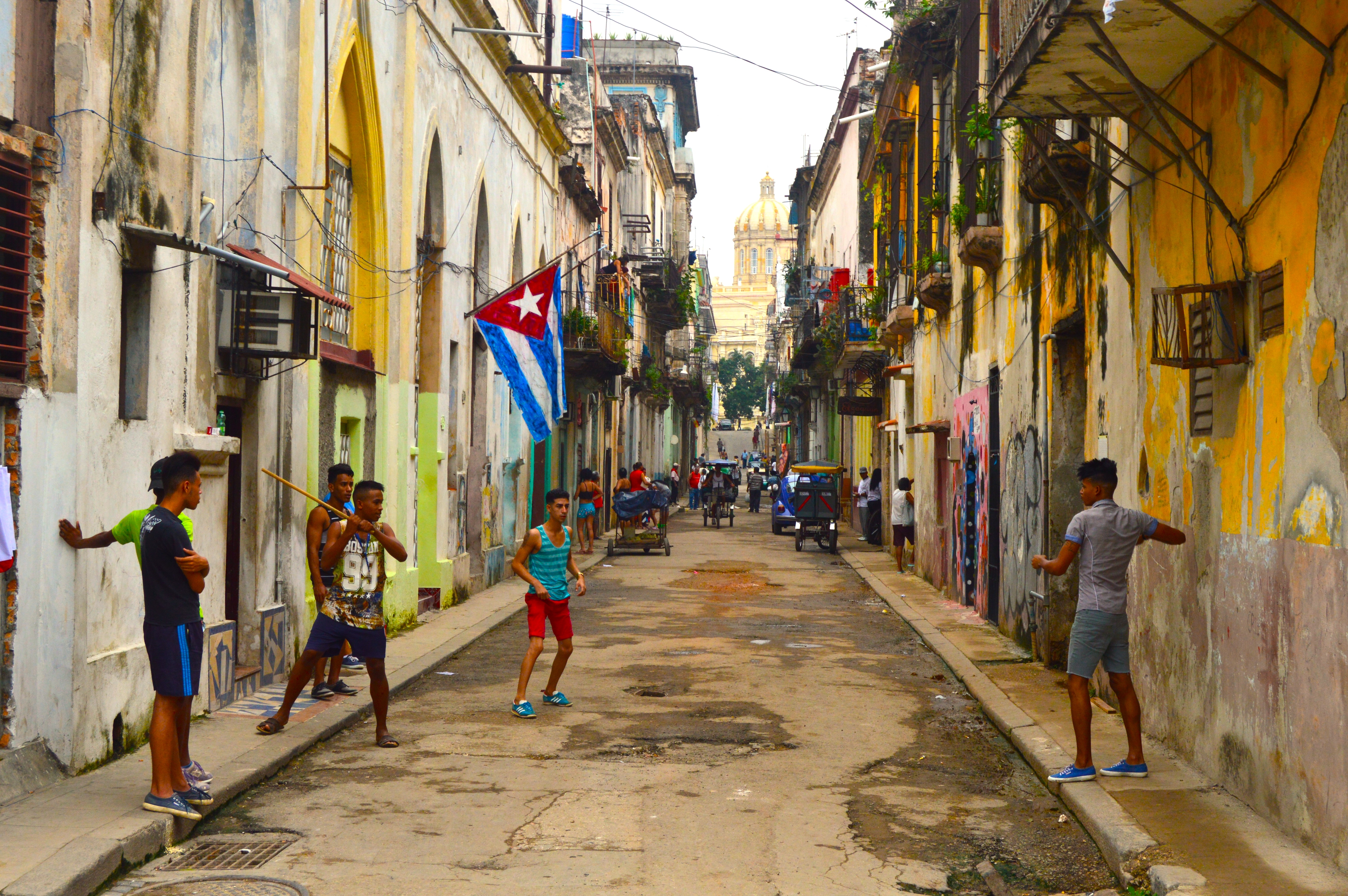 Niños jugando béisbol callejero en La Habana Vieja: juego improvisado con bate de madera